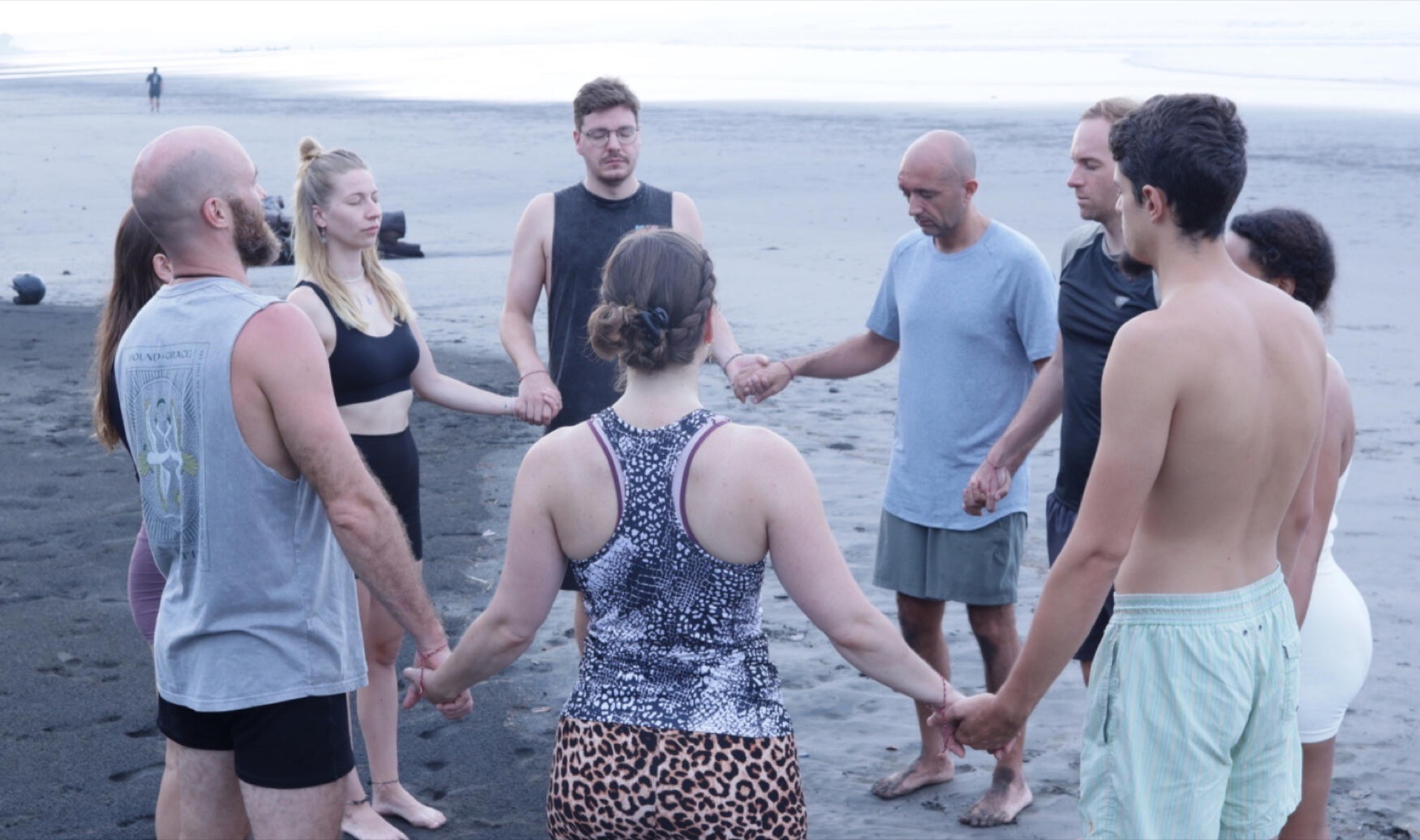 The Gaia Bali Immersion community standing together in a circle by the ocean
